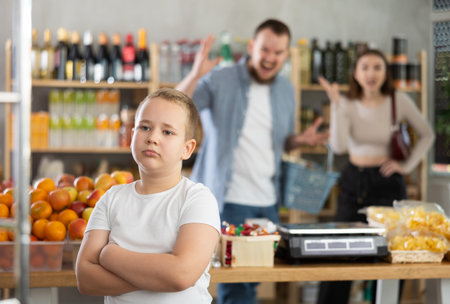Couple man and woman quarreling with boy in grocery storeの写真素材