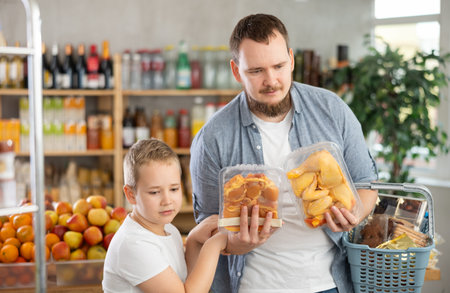 Man with son holding plastic containers with poultry parts, choose chicken meat.の写真素材