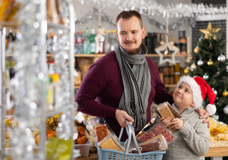 Young man with son choosing sweets at grocery storeの写真素材