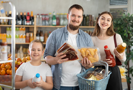 Couple of man and woman with boy choosing food in groceryの写真素材
