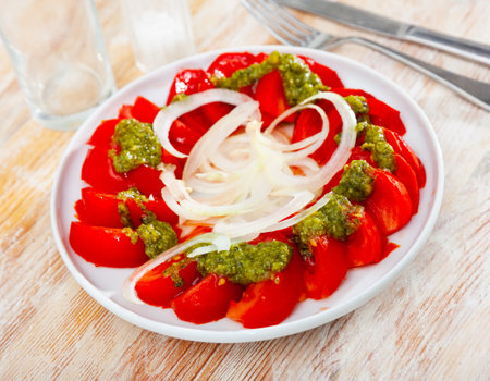 Fresh tomatoes with basil pesto sauce and onionの写真素材