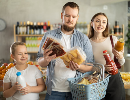 Family with various products in hands continuing shopping in grocery department of supermarketの写真素材