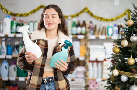 Young woman choosing cleaning spray in store during Christmasの写真素材