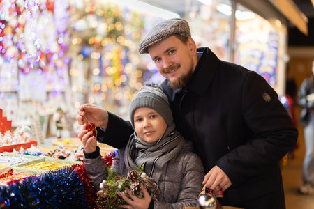 Man with son in outdoor souvenir shop examines Christmas toysの写真素材