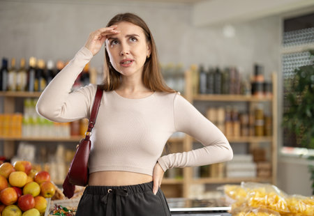Female shopper has difficulty remembering what to buy at grocery supermarketの写真素材