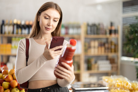 Young woman scanning qr code of tomato juiceの写真素材