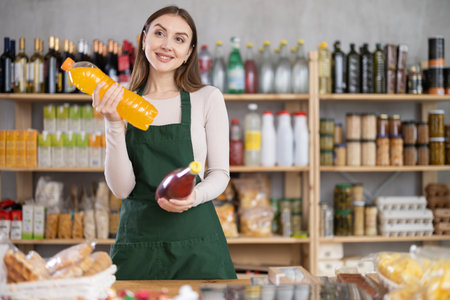 Young woman seller offering soda in grocery storeの写真素材