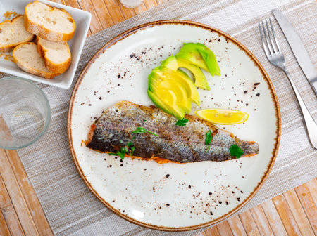 Plate with fried trout fillet with avocado in restaurante closeupの写真素材