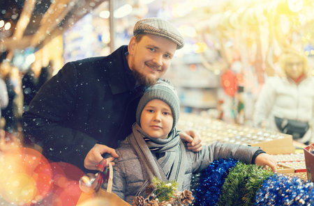 Man with son in outdoor souvenir shop examines Christmas toysの写真素材