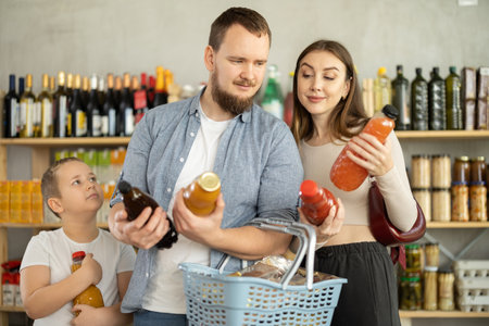 Young family with little son choosing natural juice in supermarketの写真素材