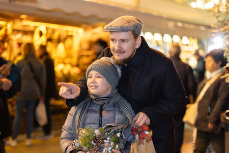 Man with son stands in middle of shopping area decorated for New Year holidaysの写真素材
