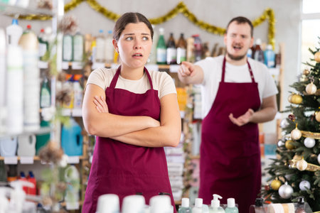 Upset salesgirl standing in festive store while colleague reprimanding herの写真素材