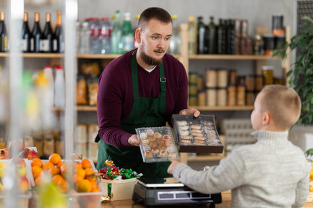 Male seller offers cookies to boy buyerの写真素材