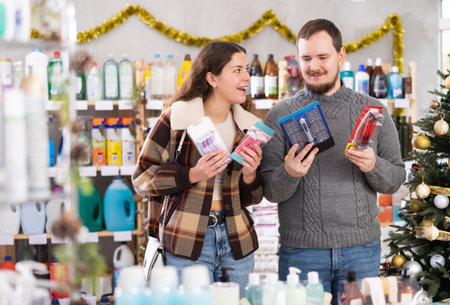 Couple choosing razors in supermarket before celebrating Christmasの写真素材