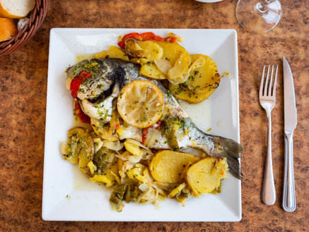 There is large piece of baked fish dorado and potato garnishの写真素材