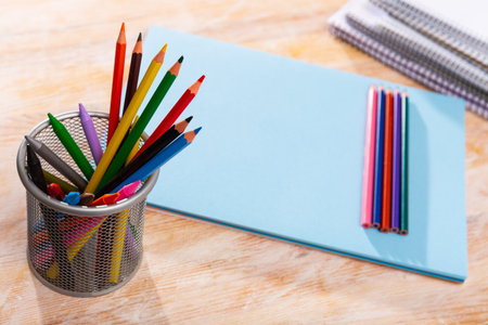 Multicolored wooden pencils on desk with papers and notebooksの写真素材