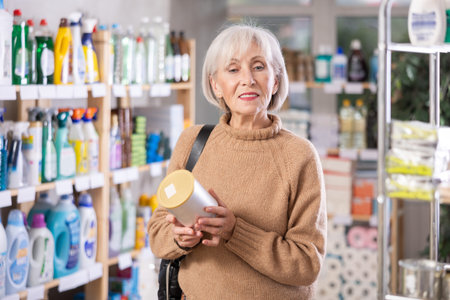 Elderly female shopper holds container in the supermarket
