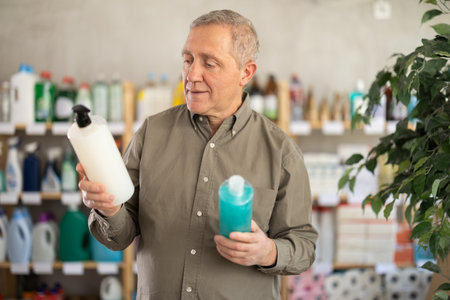 Senior man studies label and choose shampoo or shower gelの写真素材