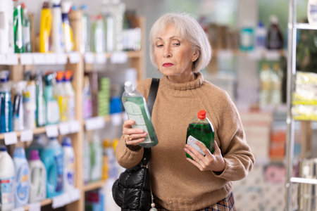 Elderly female customer diligently picking out dishwashing liquidの写真素材