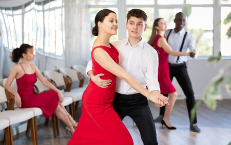 Man and Asian woman dancing waltz in couple during lesson at studio