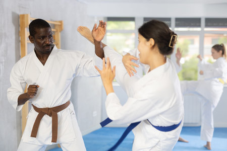 Adult man and young woman training judo techniques