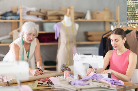 Woman sewing create wardrobe items, senior female assistant drawing paper dress pattern by curvesの写真素材