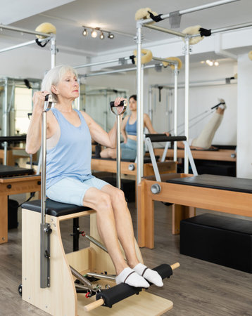 Aged woman exercising on wunda chair in pilates studio