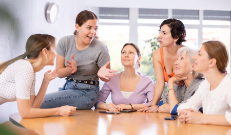 young girl student sits on table near friends and promotes version of solution of educational task