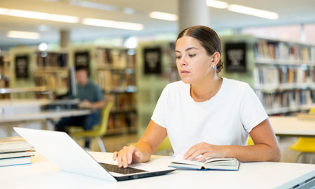 Caucasian school student girl doing research on project laptop