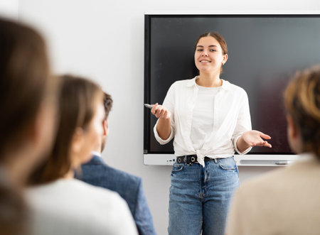 Young female teacher giving lecture to group of student