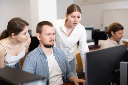 Male teacher and students studying program together on computer screen at university