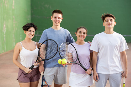 Group photo of positive young men and women standing on frontenis court after gameの写真素材