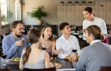 Female waitress taking order from group of friends in restaurantの写真素材