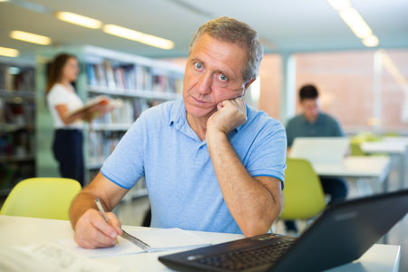 Portrait of tired mature student in public libraryの写真素材