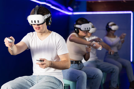 In darkened hall of gaming club, guy in VR helmet takes part in group game