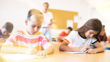 Diligent tweens listening to lecture of teacher and writing in notebooks