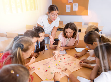 Teacher and group of kids playing board game in school
