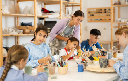 Preteen girl speaking to a circle member while processing ceramic items