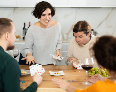 Happy group of friends playing poker cards and drinking wine