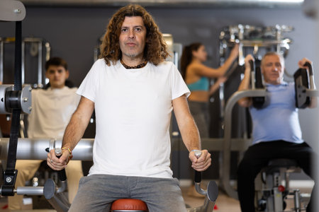 Man doing presses for triceps in exercise machine in gym
