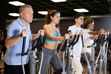 Elderly man working out on elliptical machine in gym