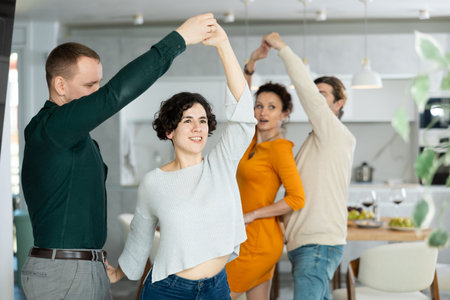 Friends dancing. Cheerful young people dancing and drinking while enjoying home party on room