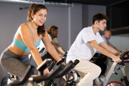 Young girl doing cardio workout on exercise bike in gym