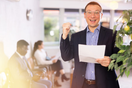 Adult man in glasses with documents stands in receptionの写真素材