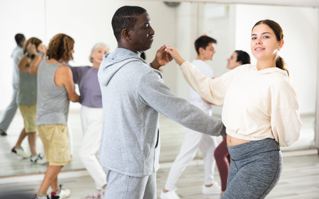 Girl learning to dance waltz paired with african american man