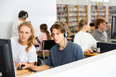 Portrait of a fifteen-year-old schoolboy in headphones at a computer