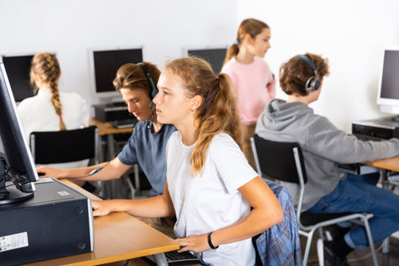 Group of teenage boys and girls learning to use computers in classroom