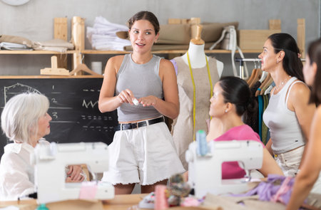 Young female teacher speaking students during dressmaking class