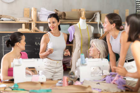 Middle-aged female teacher speaking students during dressmaking class