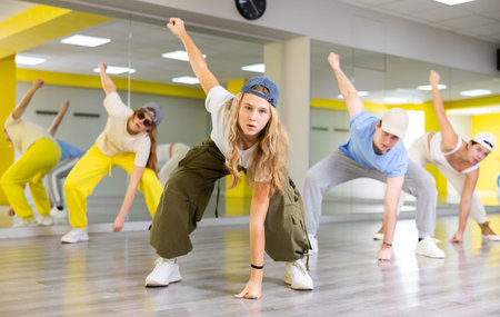 Excited positive teenage dancers having fun and learning modern dance during class in modern hall